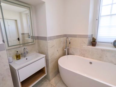 A bathroom with a bathtub and vanity sink at Treetops, Alnwick