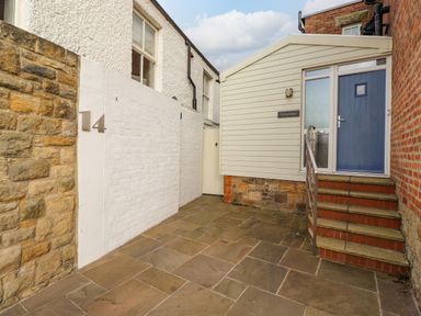 An outdoor entrance area with stone pavement stairs and a blue door at The Beach House in Alnmouth
