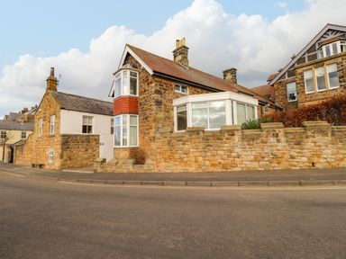 A street view of stone and brick houses with stone walls along the roadside at The Beach House in Alnmouth