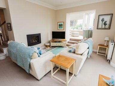 A living room with two sofas a television and a fireplace at The Beach House Alnmouth