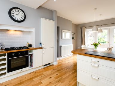 A kitchen with oven stove wooden countertops white cabinets and dining area with flowers on table at The Beach House Alnmouth
