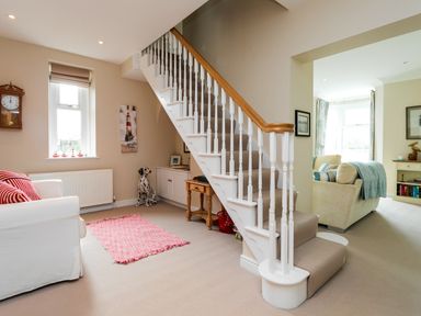 A sitting area with a staircase white sofa and small table at The Beach House Alnmouth