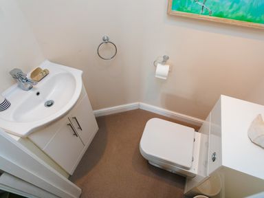 A small bathroom with a white sink cabinet and a closed toilet seat at The Beach House Alnmouth