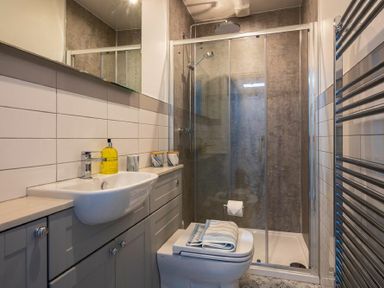 A bathroom with a sink countertop and a shower with glass doors at Wisteria Cottage in Warkworth