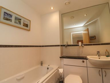 A bathroom with a bathtub toilet sink and a large mirror at Puffin View in Seahouses