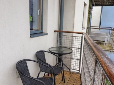 A small balcony with two black chairs and a round glass table at Puffin View in Seahouses