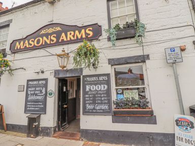 The entrance to Masons Arms pub with hanging flower baskets chalkboard menus and a parking sign at Westhill House in Warkworth