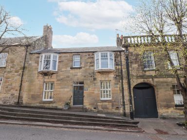 Stone building with bay windows and stairs leading to a door at Westhill House in Warkworth