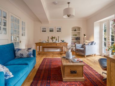 A living room with a blue sofa and dining table at Westhill House in Warkworth