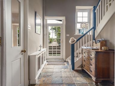 A hallway with a staircase and console table at Westhill House Warkworth