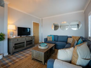 A living room with blue sectional sofa wooden coffee table and TV on wooden cabinet at Keildon in Seahouses