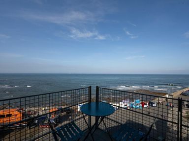 A balcony with a small round table and two chairs overlooking the sea at Keildon in Seahouses