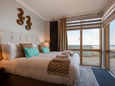 A bedroom with a double bed pillows and towels near a large window at Keildon in Seahouses