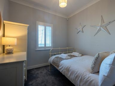 A bedroom with a bed with pillows and towels a window and a dresser with a lamp at Keildon in Seahouses
