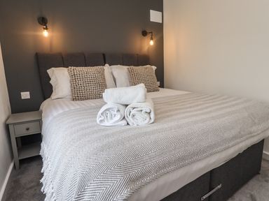 A bedroom with a bed with pillows and blankets and rolled towels on the bed at Muscle Shoals in Seahouses