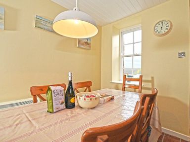 A dining room with a table covered by a tablecloth and four wooden chairs at Sandpiper Cottage Low Newton-by-the-Sea