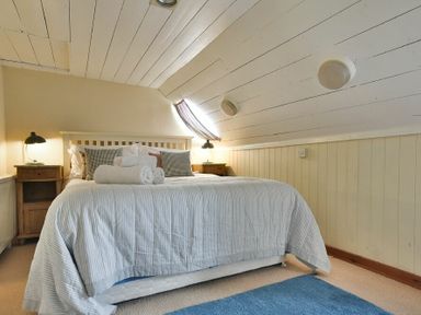 A bedroom with a bed pillows rolled towels blue rug and wooden bedside tables at Sandpiper Cottage Low Newton-by-the-Sea