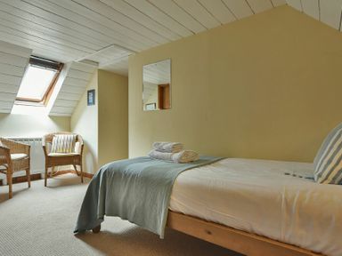 A bedroom with a single bed two wicker chairs and a skylight window at Sandpiper Cottage Low Newton-by-the-Sea