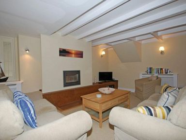 A living room with sofas a wooden coffee table a fireplace a television and books at Grange Cottage in Alnmouth
