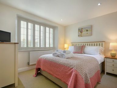 A bedroom with a double bed with folded towels on top and bedside tables with lamps at Grange Cottage in Alnmouth