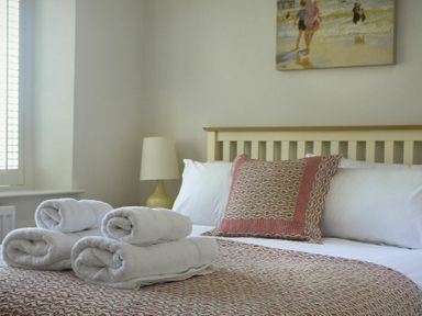 A bedroom with a bed with pillows and folded towels on the bed at Grange Cottage in Alnmouth