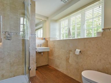 A bathroom with a shower enclosure a sink a toilet and a window with blinds at Grange Cottage in Alnmouth