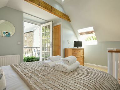 A bedroom with a bed covered with a textured bedspread and towels on top at Grange Cottage in Alnmouth