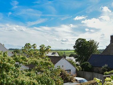 A view of rooftops trees and countryside under a blue sky at Grange Cottage in Alnmouth