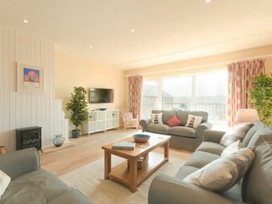 A living room with sofas and a wooden coffee table near large windows at The Boathouse (Alnmouth) in Alnmouth