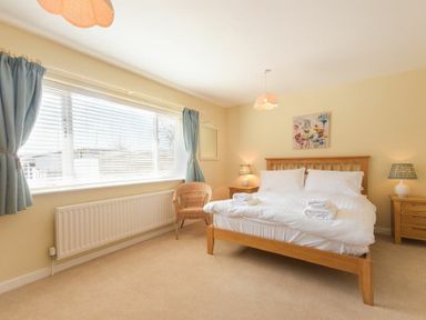 A bedroom with a double bed and blue curtains at The Boathouse (Alnmouth) in Alnmouth