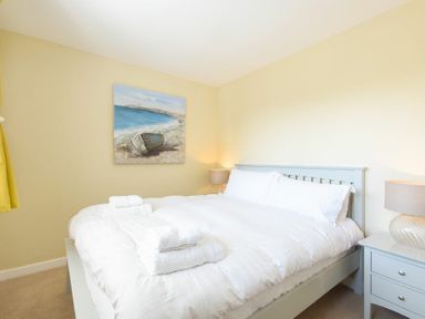 A bedroom with a double bed bedside tables and lamps and a painting on the wall at The Boathouse in Alnmouth