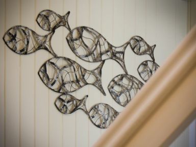 Metal wall art shaped like fish on a beige paneled wall at The Boathouse (Alnmouth) in Alnmouth