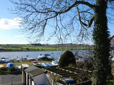A riverside with boats on the grass and trees at The Boathouse Alnmouth