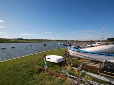 A riverside scene with boats on the water and stored on grass at The Boathouse in Alnmouth