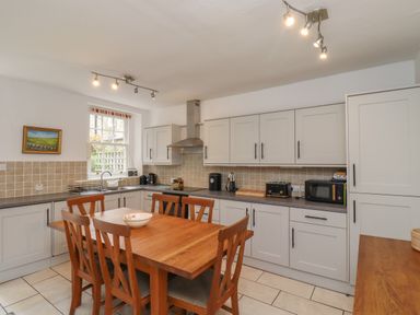 A kitchen with wooden dining table and chairs and light grey cabinets at Avocet Cottage in Bamburgh