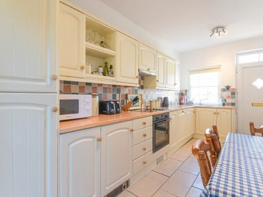 A kitchen with cream cabinets a microwave toaster and oven at Dunlin Cottage in Bamburgh