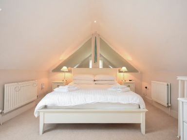 A bedroom with a double bed two bedside tables with lamps and radiators on the walls at High Tide in Newton-by-the-Sea
