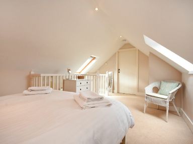 A bedroom with a bed white dresser wicker chair and skylight windows at High Tide in Newton-by-the-Sea