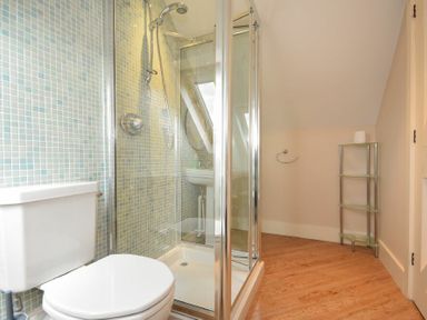 A bathroom with a white toilet shower enclosure and glass shelving unit at High Tide in Newton-by-the-Sea