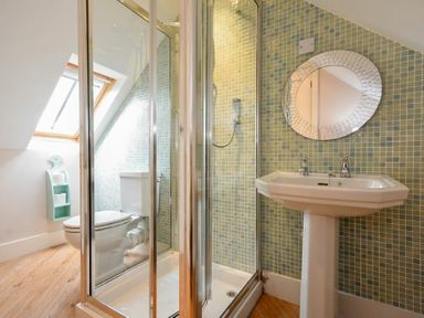 A bathroom with a shower enclosure toilet sink and round mirror at High Tide in Newton-by-the-Sea