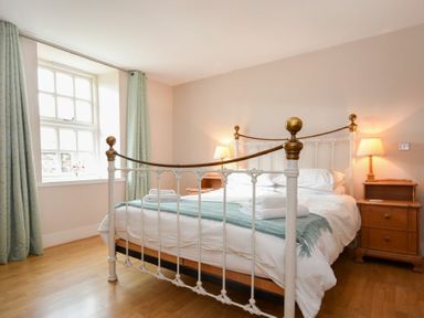 A bedroom with a metal bed frame white bedding wooden nightstands and lamps at High Tide in Newton-by-the-Sea