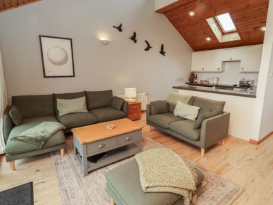 A living room with seating and kitchen counter at Links View in Embleton