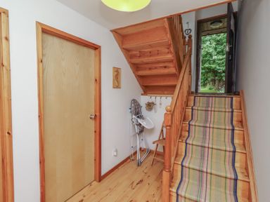A hallway with a staircase and door at Links View in Embleton