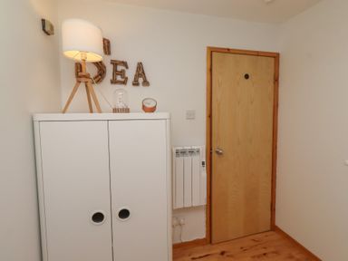A hallway with a cupboard, lamp, clock, and door at Links View in Embleton