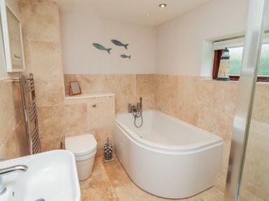 A bathroom with a bathtub, toilet, and sink at Links View in Embleton