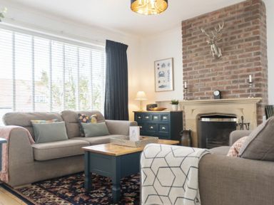 A living room with sofas a coffee table and a brick fireplace at Sea Croft in Beadnell