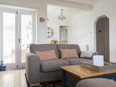 A living room with a gray sofa and a wooden coffee table near glass doors at Sea Croft in Beadnell