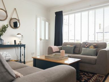 A living room with sofas a coffee table and two round mirrors on the wall at Sea Croft in Beadnell
