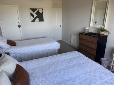 A bedroom with two beds and a dresser at Sea Croft in Beadnell