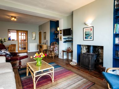 A living room with a fireplace tulips on a coffee table and chairs at Old Coastguard Cottages in Amble